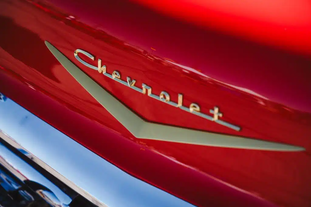 Close up of a vintage red Chevrolet emblem with chrome and gold detailing, showcasing the classic design during the Luna y Sol Community Habitat car show